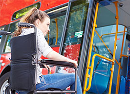 Young girl in wheelchair boarding a bus.